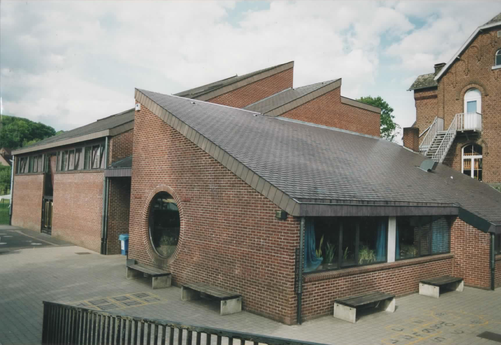 Bâtiment scolaire en brique, toiture ardoise, fenêtre ronde