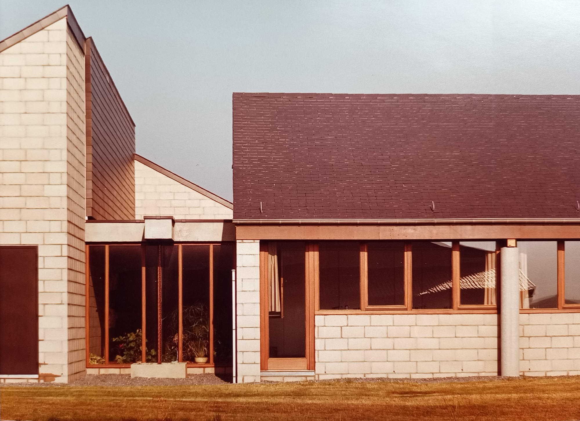 Façade en blocs blancs, toiture ardoise et châssis bois