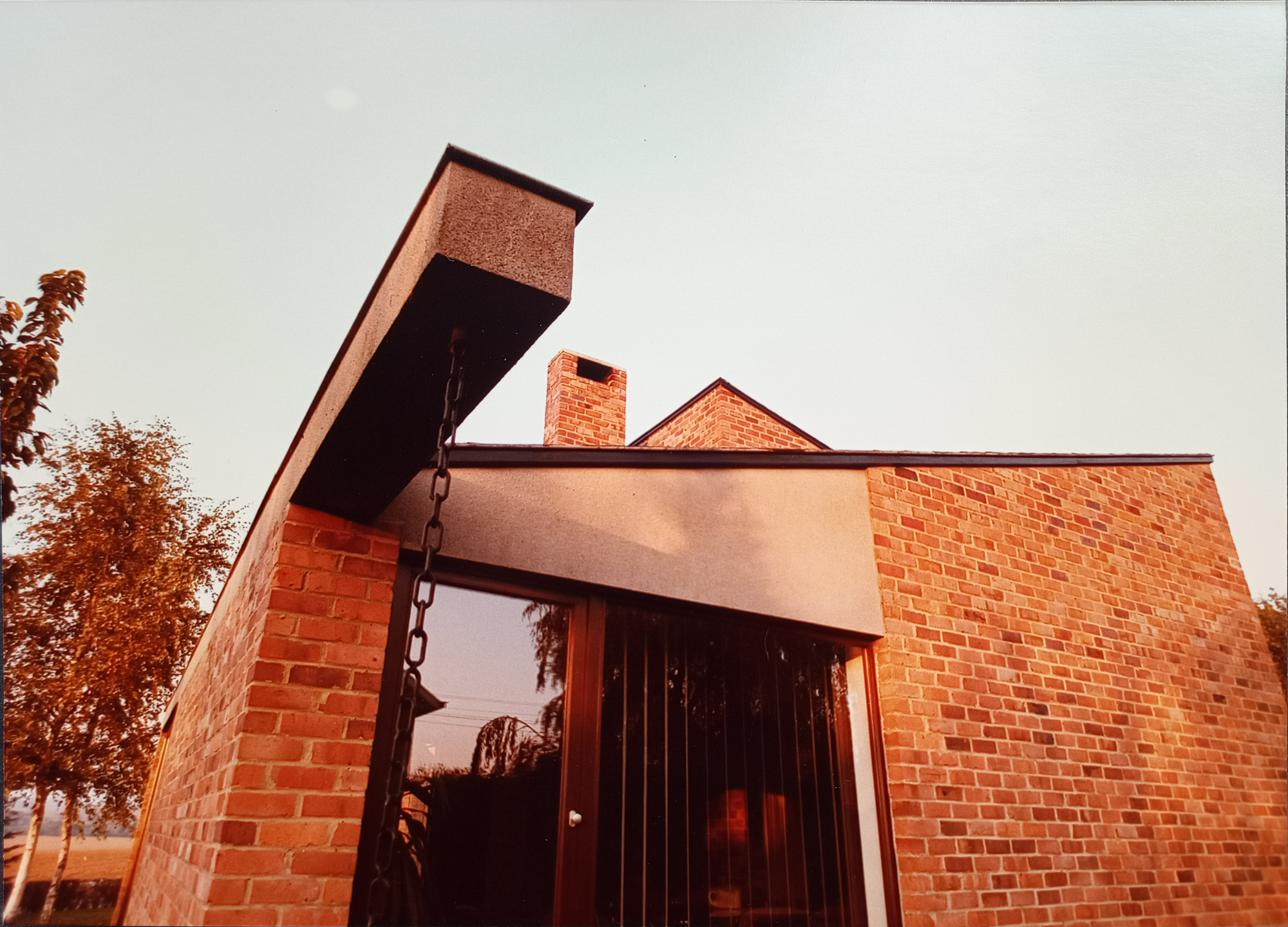Entrée en brique avec avant-toit suspendu et chaîne