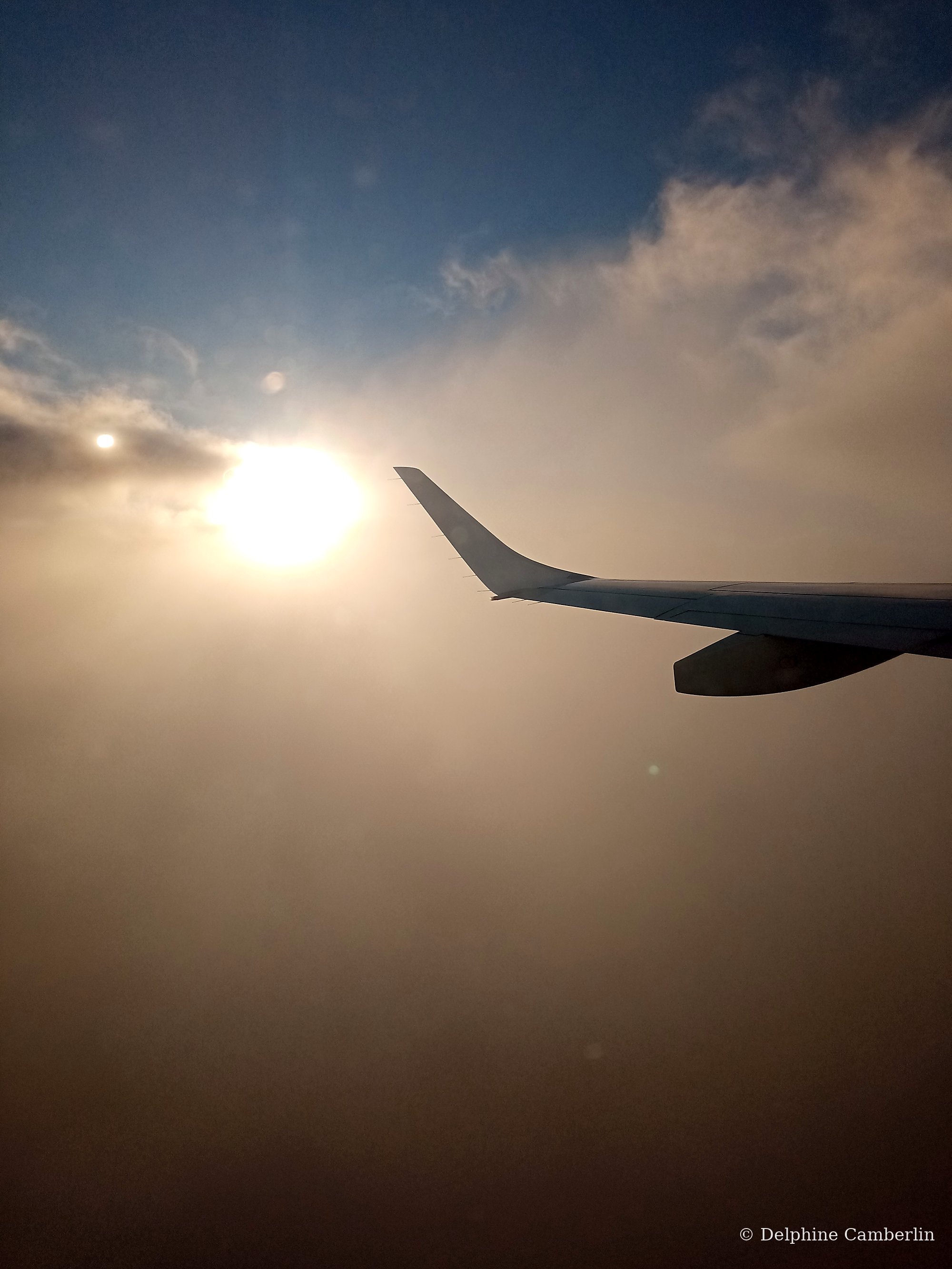 Plane wing above the clouds at sunrise — carbon offset for flights