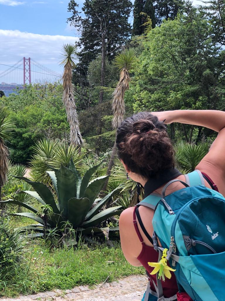 Photographer with camera and travel backpack shooting Lisbon's bridge from Jardim Botânico